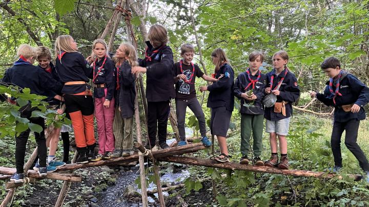 Juniorspejdere på raftebro over en å